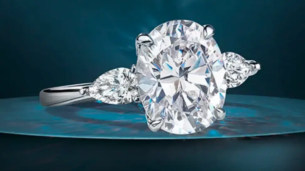 An image of an oval-cut diamond ring in a silver band with flanking smaller pear-cut diamonds.