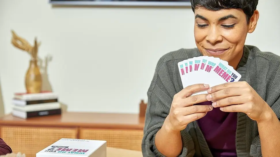 A woman playing 'What Do You Meme?' with her friends.
