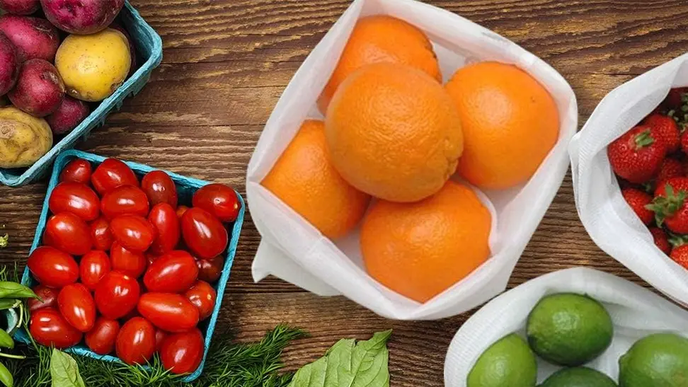 Several reusable grocery bags being used to transport fruits and vegetables.