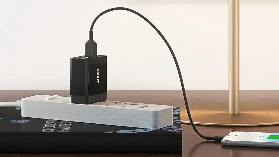 An Anker USB wall charger being used to charge a smartphone.