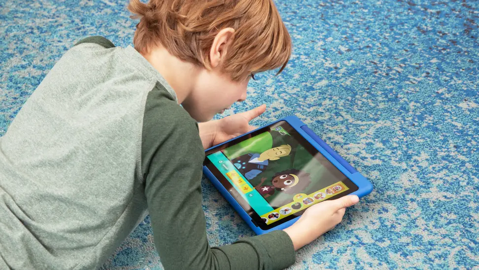 Child on floor watching fire tablet with PBS Kids Wild Kratts episode on the screen.
