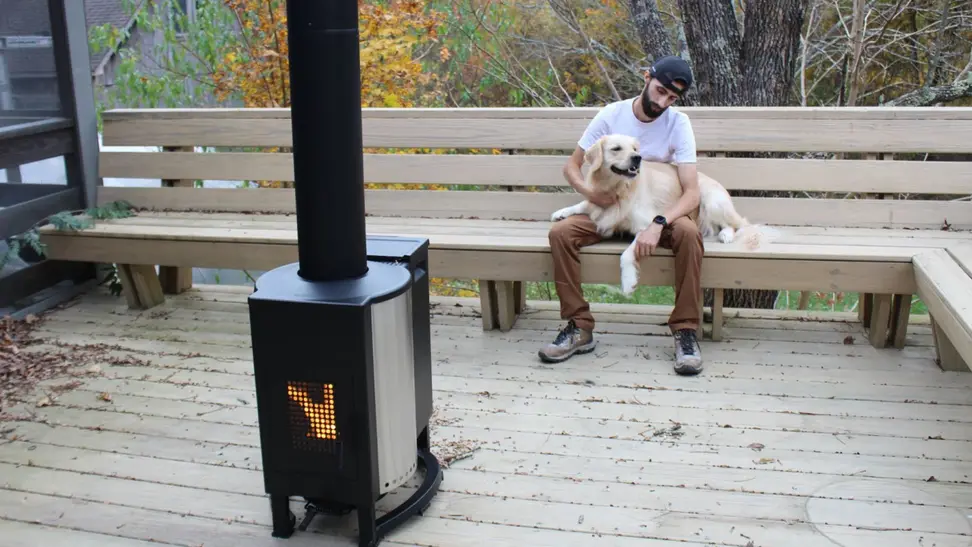 Fire burning inside the Solo Stove Patio Heater with a person and dog sitting on a bench in the background.