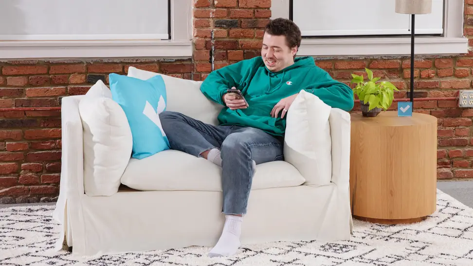 A person looking at their phone while sitting in a white lounge chair