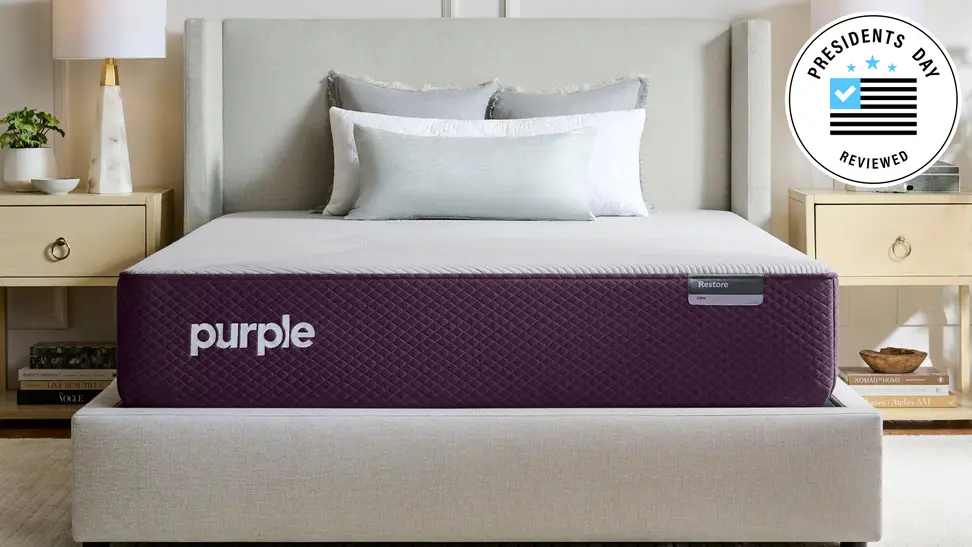 A Purple Restore hybrid mattress in a bedroom with the Presidents Day Reviewed badge in the top right corner.