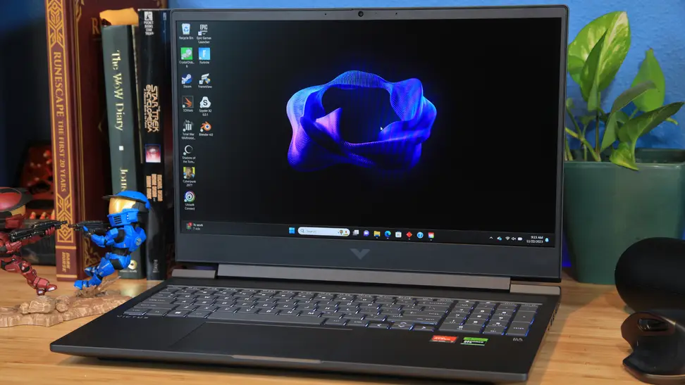 The HP Victus 16 sitting atop a desk with a multitude of books and two Halo Spartan figures.
