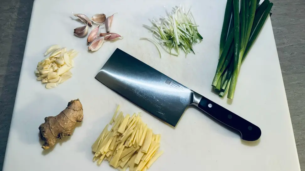 The Zwilling Professional Cleaver Knife on a cutting table surrounded by cut veggies.