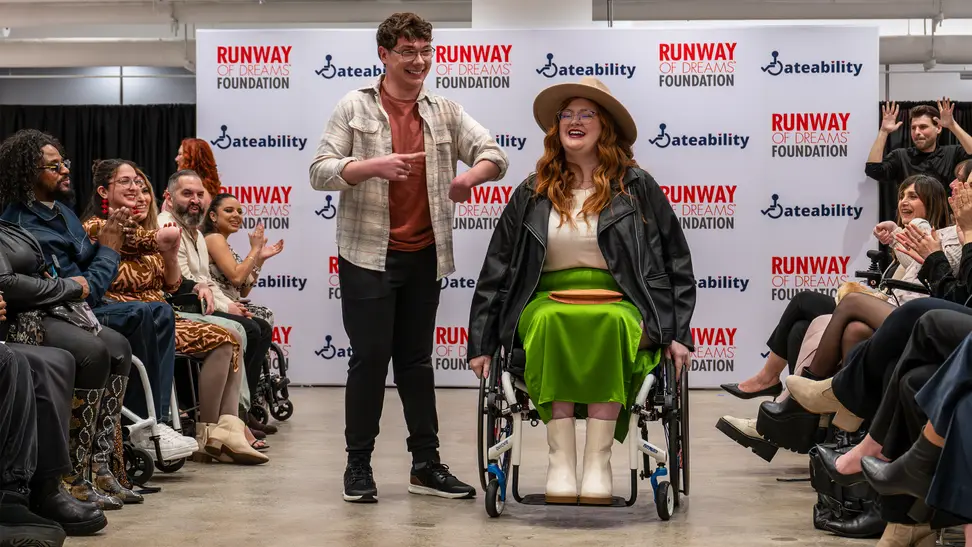 Two disabled people on runway showcasing clothes.