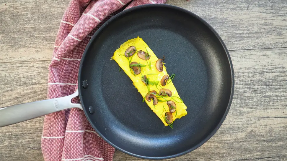 Eggs frying in an OXO nonstick pan on a stovetop.