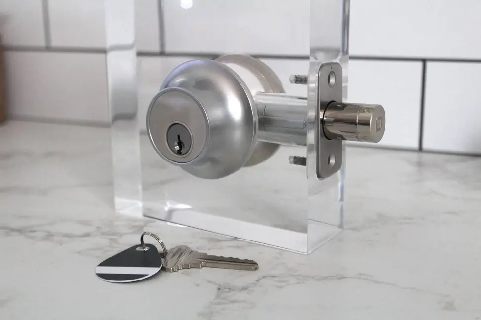 The Level Lock Plus Connect smart deadbolt set up on a test stand with a key and fob on the counter