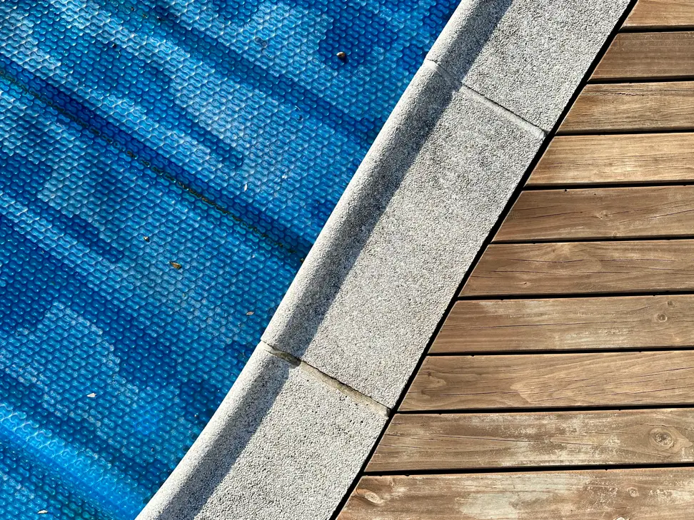 A blue solar pool cover sits on top of a pool.
