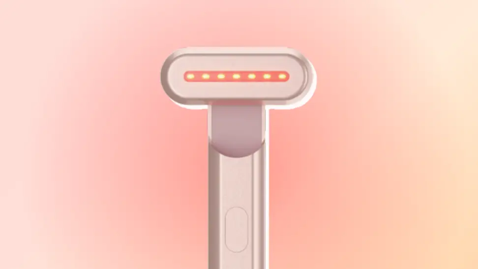 SolaWave Wand in rose gold against a red and orange background