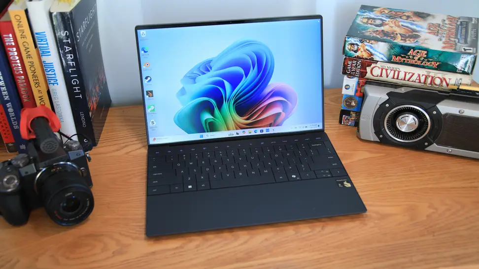 The 2024 Dell XPS 13 9345 laptop sitting on a desk next to a camera and several books.