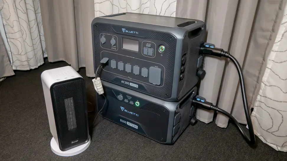 A Bluetti AC300+B300 Home Battery Backup appears in a carpeted room with a Govee electric space heater for testing.