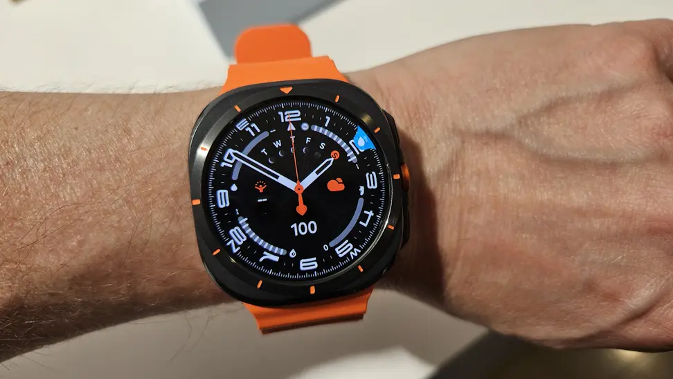 Person wearing the Samsung Galaxy Watch Ultra on their wrist with a neon orange band.