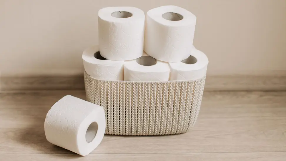 Six rolls of toilet paper in a beige wicker basket