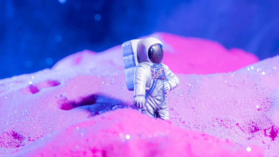 toy astronaut walking the pink sands of a planet