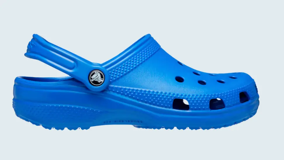a classic blue Croc clog sits on a light blue background