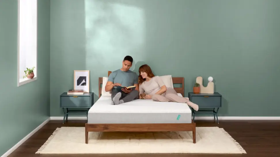 A couple sitting on a Tuft and Needle mattress.