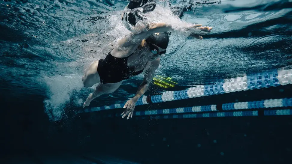 woman wearing black one piece swims breaststroke while wearing FORM smart goggles