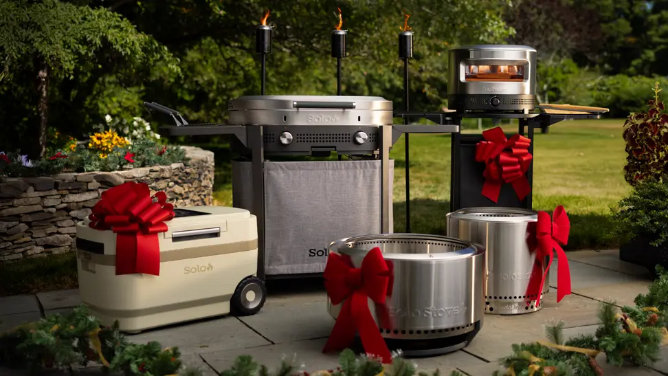 A festive outdoor display featuring a Solo Stove pizza oven and other Solo Stove products adorned with red bows, perfect Christmas gift ideas for outdoor cooking enthusiasts.