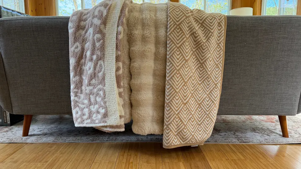 Three throw blankets placed on a couch