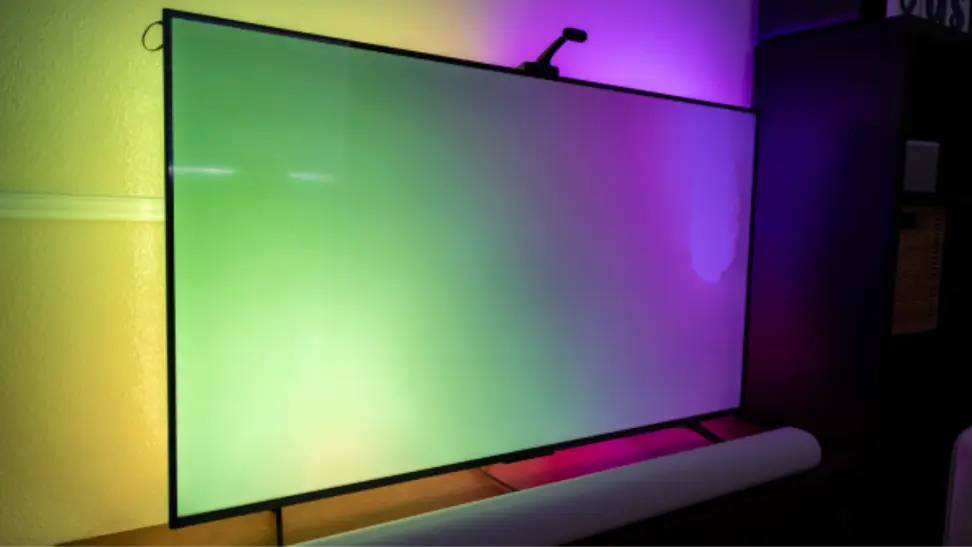 Govee TV Backlight 3 shown behind a TV displaying yellow, green, and purple lighting.