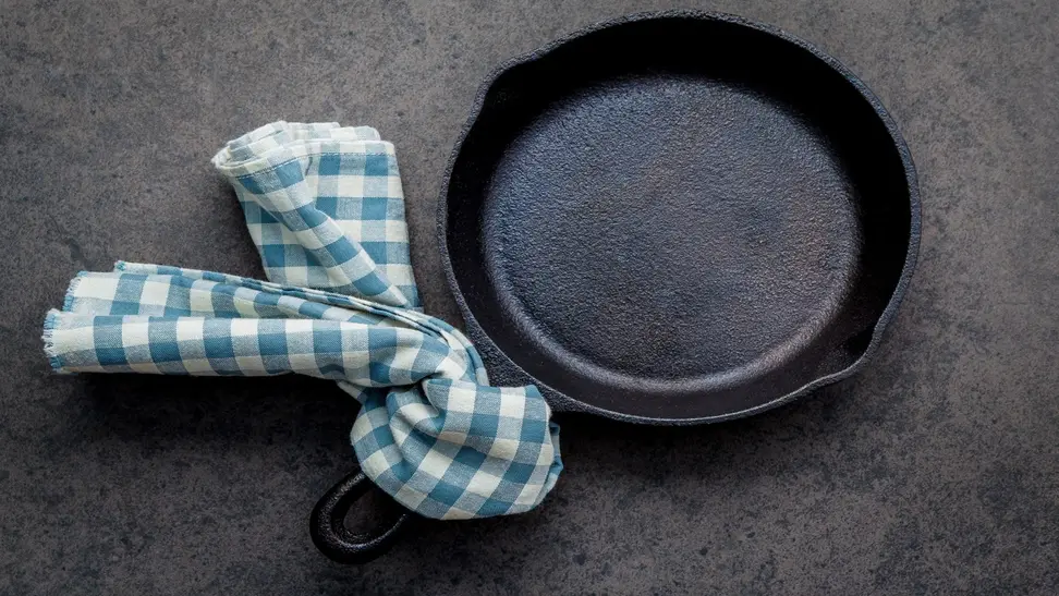 Dirty cast iron with blue and white checkered towel tied to the handle